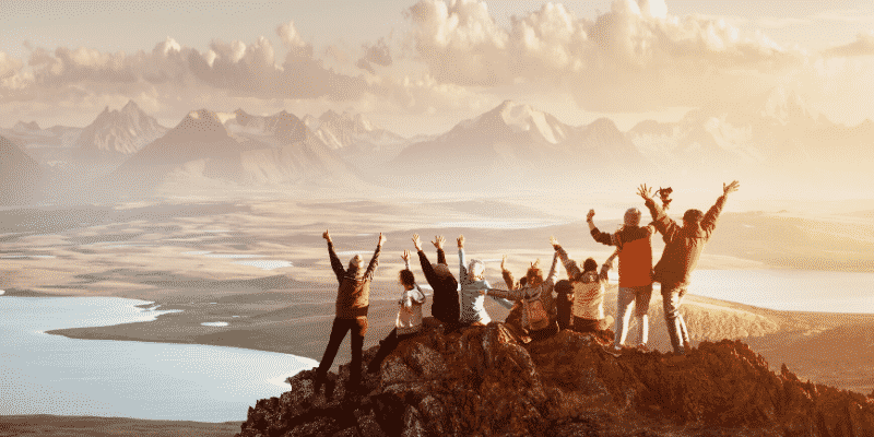 group-on-top-of-mountain-with-hands-in-air